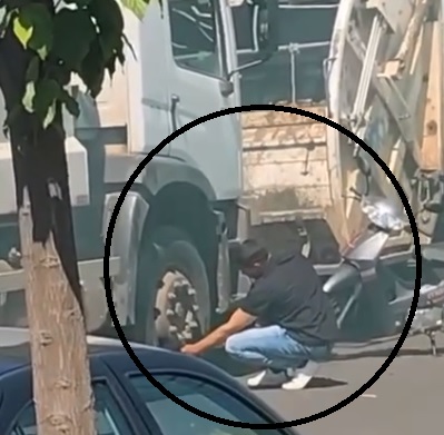  Funcionarios pretendiendo desinflar el neumático de uno de los camiones para evitar que salgan a cumplir el servicio.